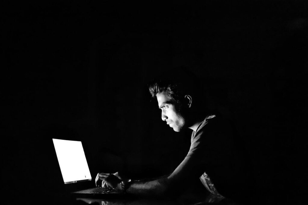 Worried user in the dark staring at  laptop 